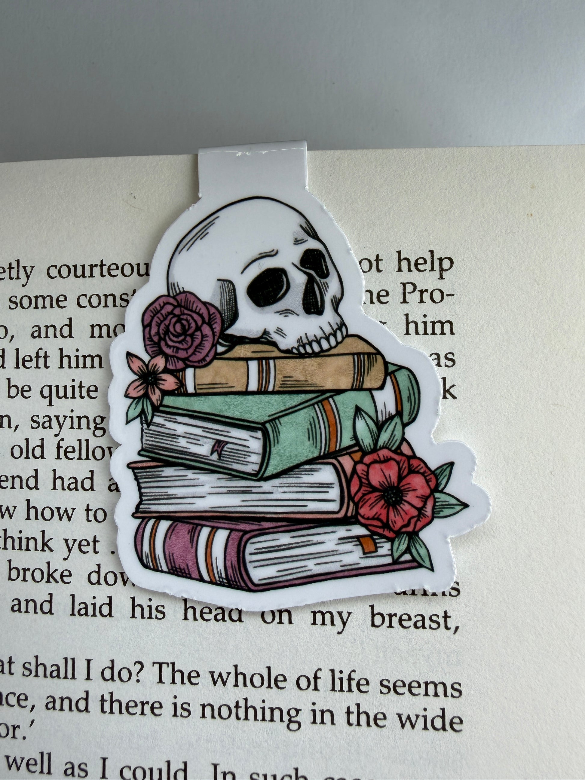 Decorative sticker with skull, books, and flowers on a book page