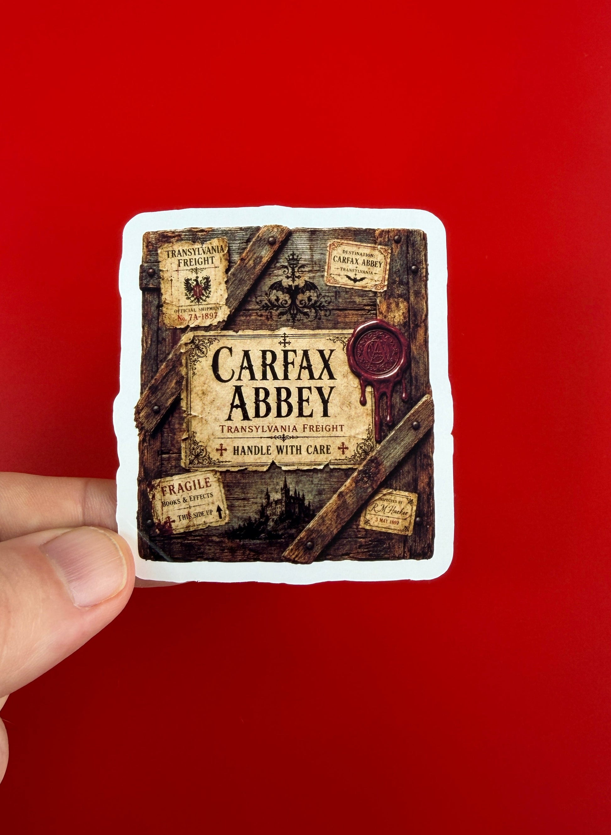 Hand holding a small square object with 'Carfax Abbey' branding against a red background
