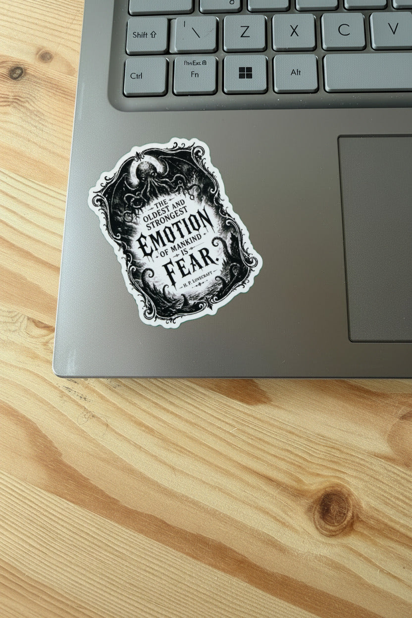 Sticker on a laptop with text 'Emotion of Madness' on a wooden surface