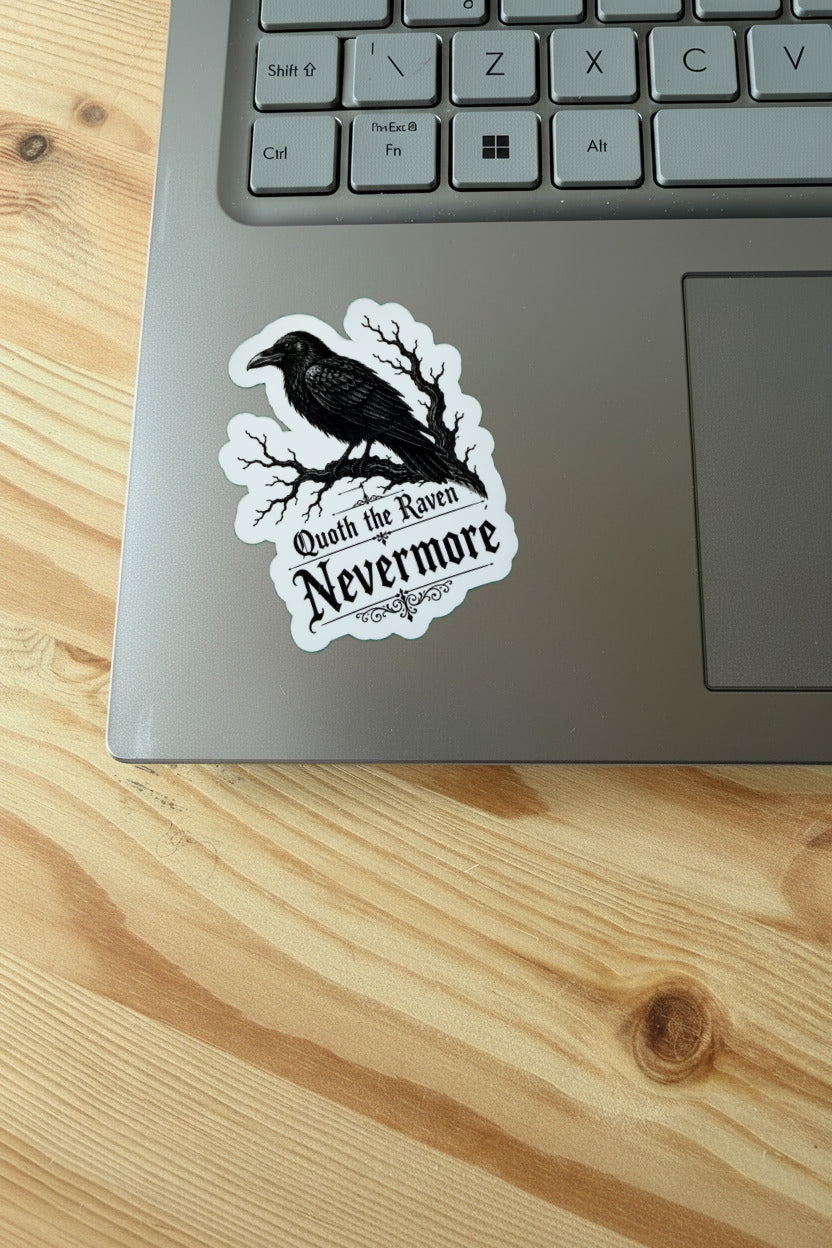 Laptop with a 'Nevermore' sticker featuring a raven on a wooden surface
