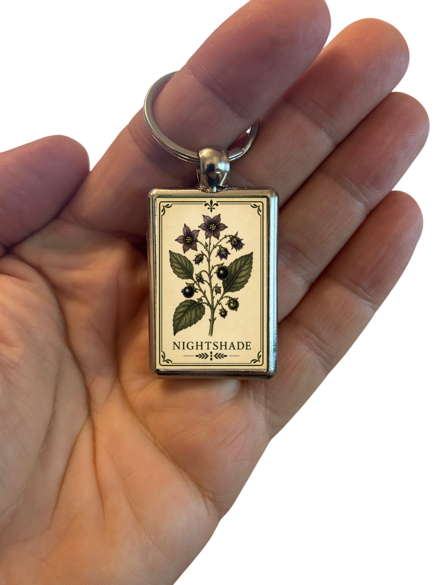 Keychain with 'Nightshade' charm in a hand on a white background