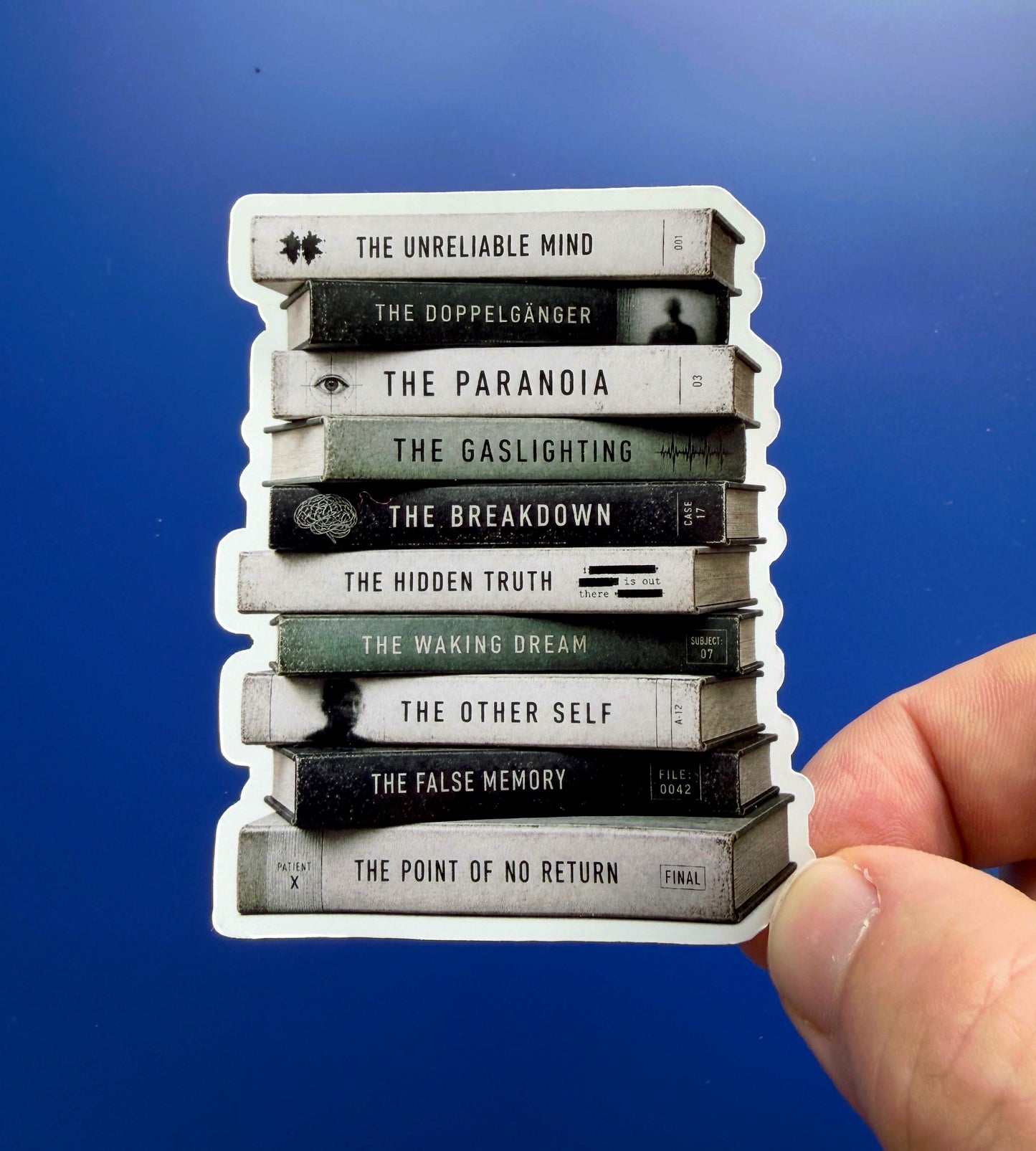 Stack of books with titles held by a hand against a blue background