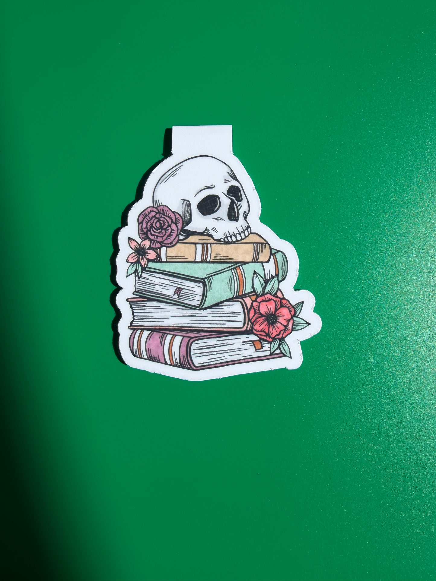 Sticker with a skull, books, and flowers on a green background